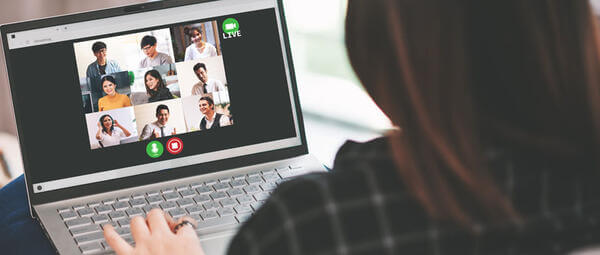 Žena zapojená do videochatu na svojom notebooku, na ktorom sa zobrazuje prebiehajúca virtuálna konverzácia.